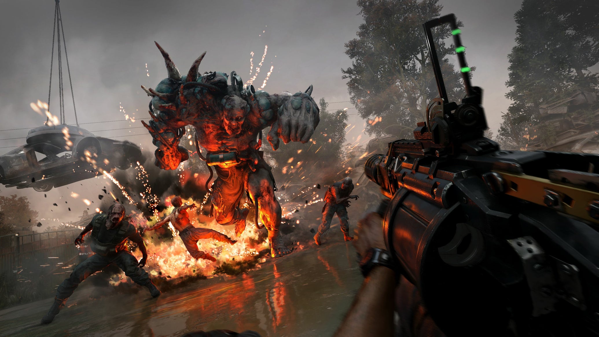 A huge musclebound zombie charging at the gun-wielding player in Dying Light: The Beast, with explosions and some smaller zombies. - 1
