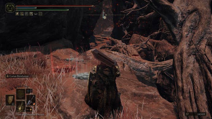 A warrior walks over large branches in the Abandoned Cave in Elden Ring.