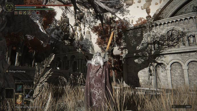 A warrior approaches a building with a large shadow of a tree on it in Crumbling Farum Azula in Elden Ring.