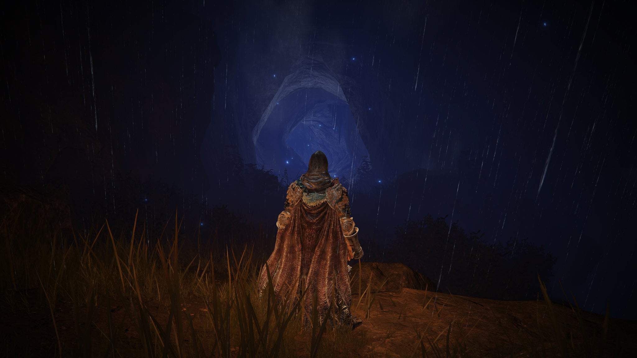 The player in Elden Ring: Shadow Of The Erdtree stands in front of a dark blue cave mouth tunnel. - 8
