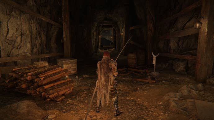 The player in Elden Ring stands at the entrance to Gael Tunnel, with their back to the camera and sword in hand.