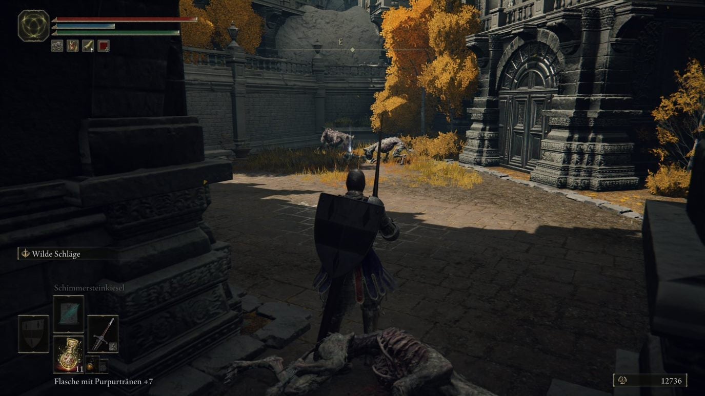 A warrior approaches some dogs eating a carcass near some doors in Leyndell, Royal Capital in Elden Ring.