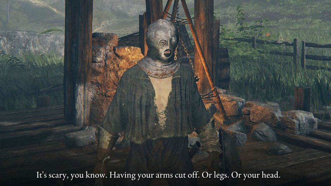 The player character in Elden Ring stands, dressed in rags and wearing an iron mask on their head, stands in a ruined house. An NPC, off screen, has said &ldquo;It&rsquo;s scary you know. Having your arms cut off. Or legs. Or your head."