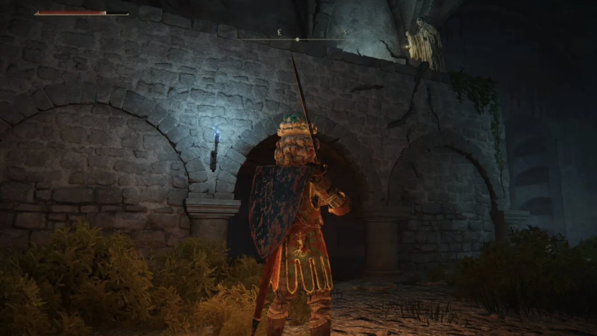 elden ring player facing secret entrance near end of roads end catacombs