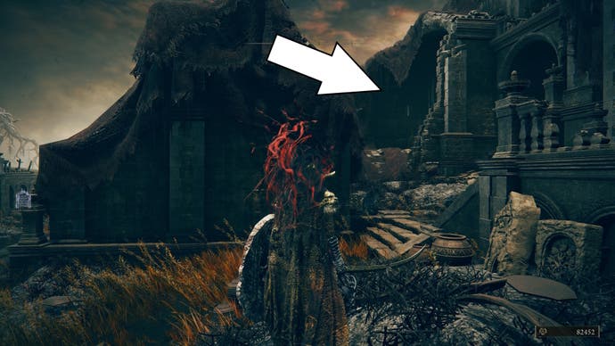 A white arrow points to a destroyed building in the burnt ruins of Shadow of the Erdtree, showing the way to the Blade of Mercy talisman.