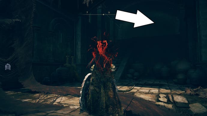 A white arrow points to a staircase in a building in the burnt ruins of Shadow of the Erdtree and shows the way to the Blade of Mercy talisman