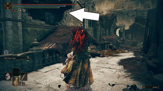 A white arrow points toward an opening on the roof of a ruined building in the Scorched Ruins of Shadow of the Erdtree, showing the way to the Blade of Mercy Talisman