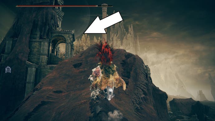 A white arrow points toward some arches on a roof in the Scorched Ruins of Shadow of the Erdtree, showing the way to the Blade of Mercy Talisman