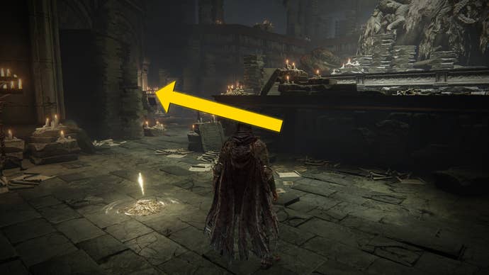 The player in Elden Ring: Shadow Of The Erdtree stands next to the Storehouse First Floor Site Of Grace. A yellow arrows points around the left corner.