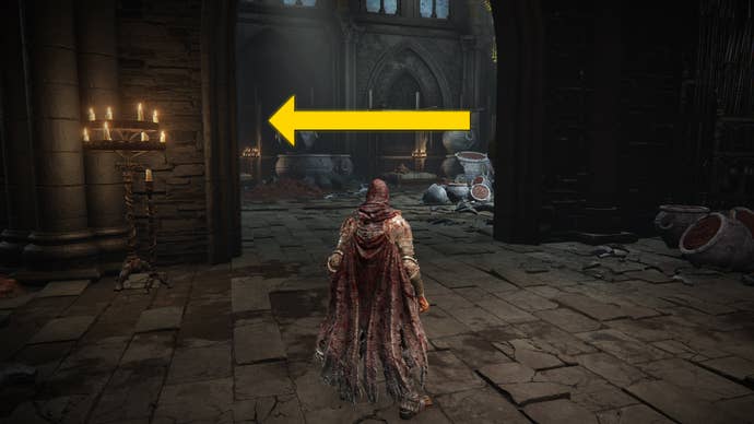The player in Elden Ring: Shadow Of The Erdtree approaches the entrance to a large hall area below the Shadow Keep. A yellow arrow points to the left of the hall.