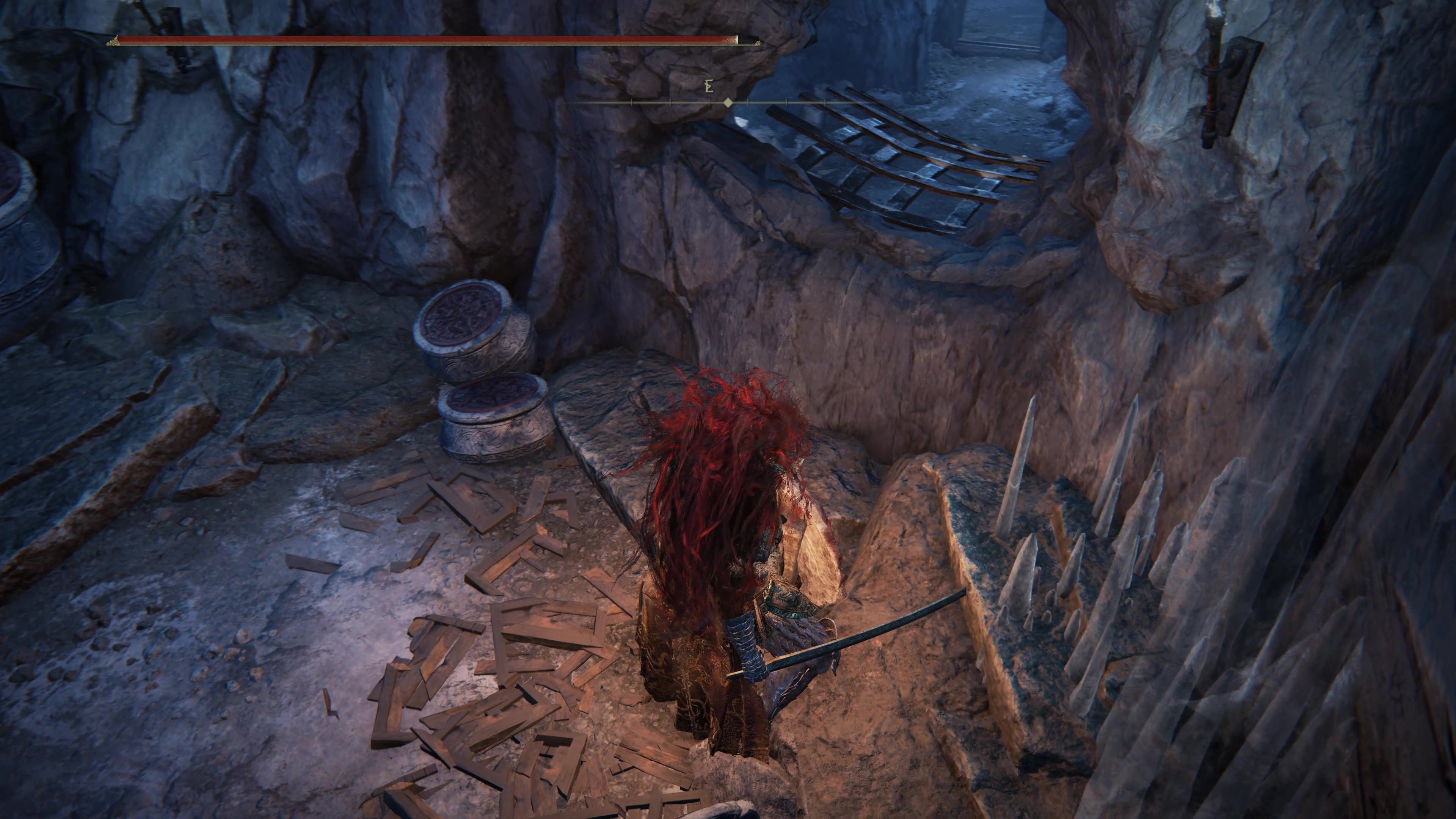 A warrior approaches a small opening in the cave wall  in the Belurat Gaol in Shadow of the Erdtree.