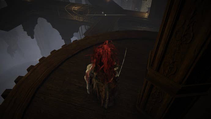 A warrior prepares to jump to a new platform in the Storehouse loft on the way to the Shadow Keep’s Back Gate in Elden Ring Shadow of the Erdtree.