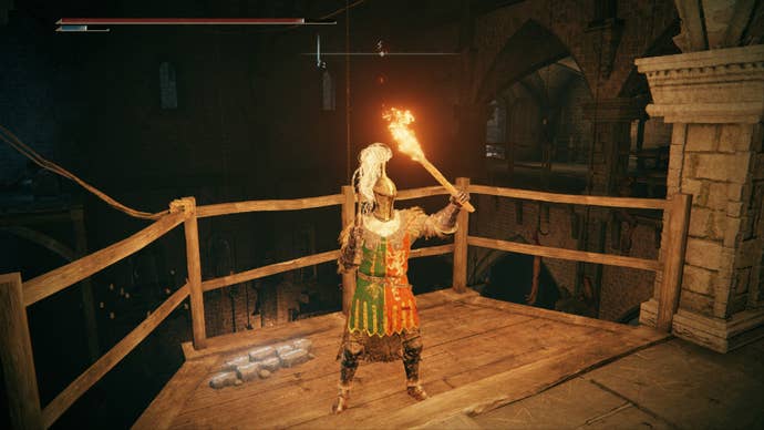 Elden Ring player stands holding a torch on a balcony overlooking the great hall of Stormveil Castle