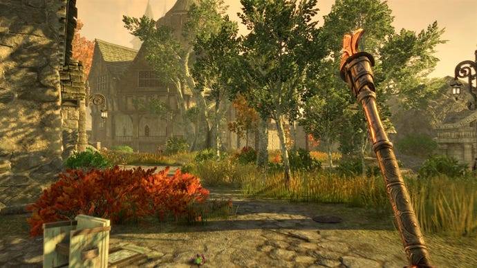 The player holds a staff in one hand as they walk through the streets of a city in The Elder Scrolls Online's Gold Road chapter