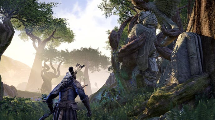 An archer walks through a forest with a huge statue built into the trunk of a tree in the Gold Road Chapter of The Elder Scrolls Online