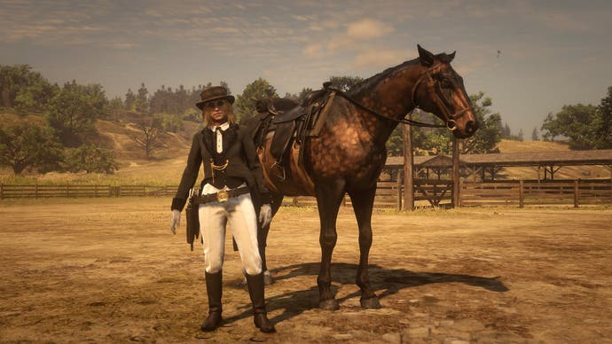 A female-presenting character in black boots, white trousers, black tail coat and black hat, stands in front of a handsome horse in a dusty, arid landscape. They have competed in a dressage competition in Red Dead Online.