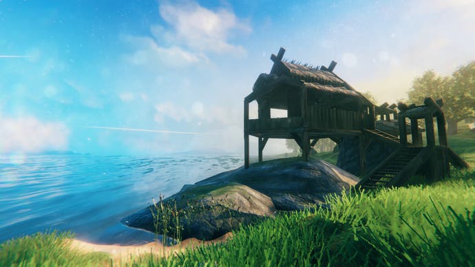 A log cabin built on stilts near the sea. It's an idyllic setting - bright blue skies and warm yellow sand, with some verdant green grass around.