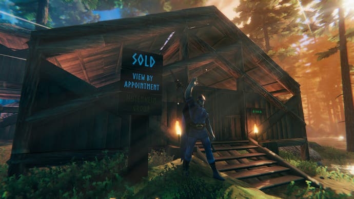 A Valheim player cheers, standing in front of a wooden cabin they have clearly just bought - as evidenced by the "sold" sign right next to them.