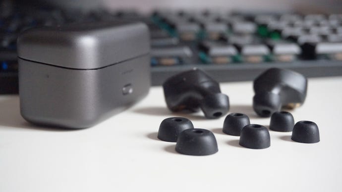 A photo of the EPOS GTW 270 Hybrid wireless earbuds next to their case and various ear seal options