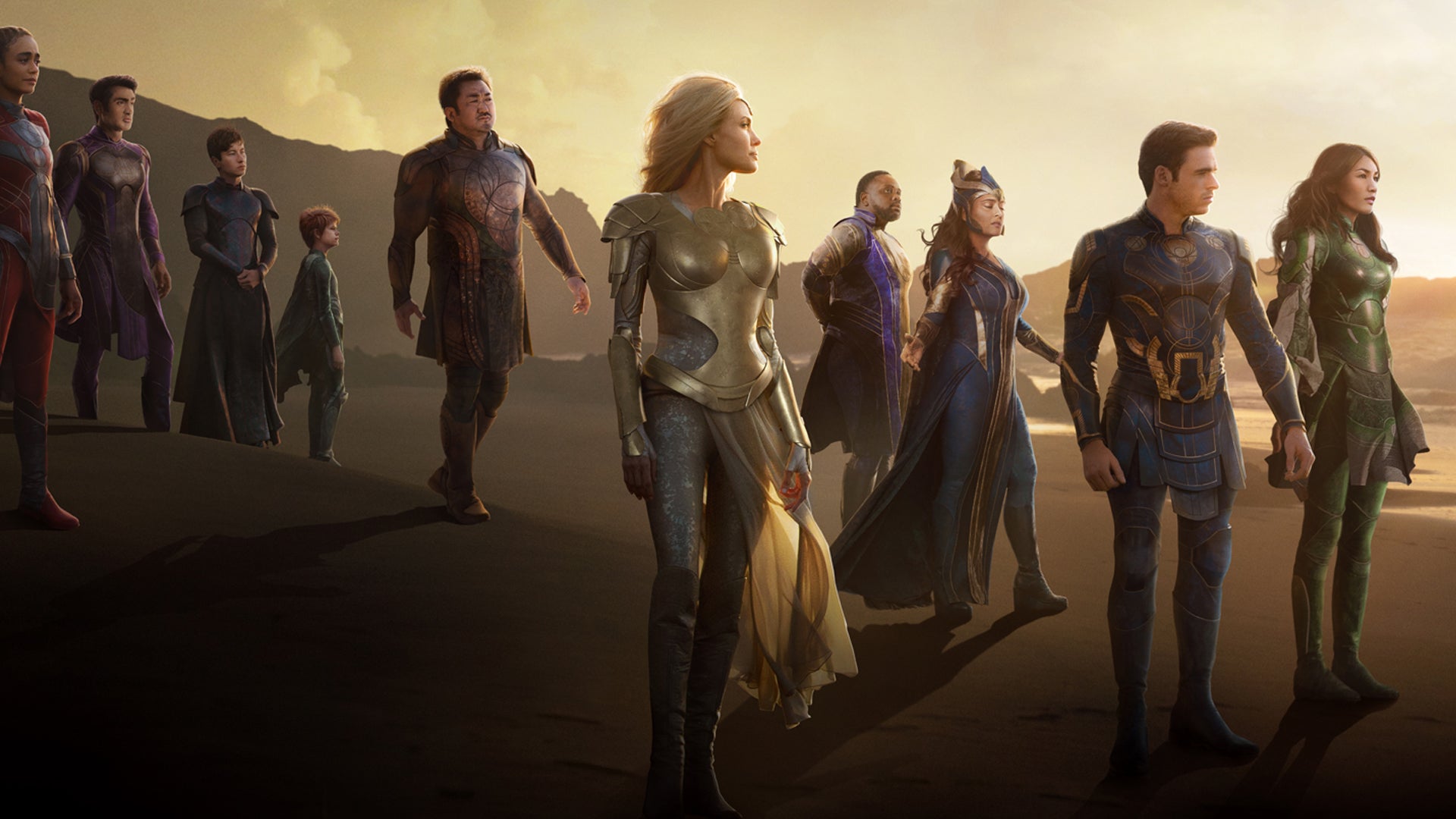 A poster for Eternals showing the main cast of characters stood on a beach.