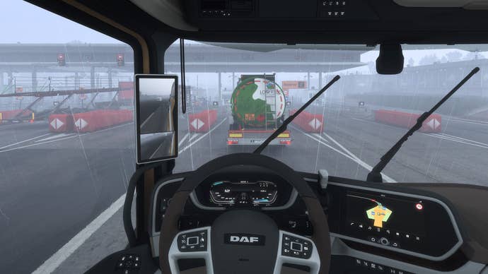 A screenshot from Euro Truck Simulator 2, showing the inside of a cab on a motorway on a rainy day. It’s anything but glamorous.