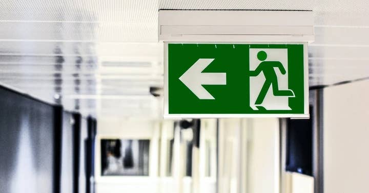 A picture of a green exit sign with an arrow pointing left and a pictogram of a person running through a door