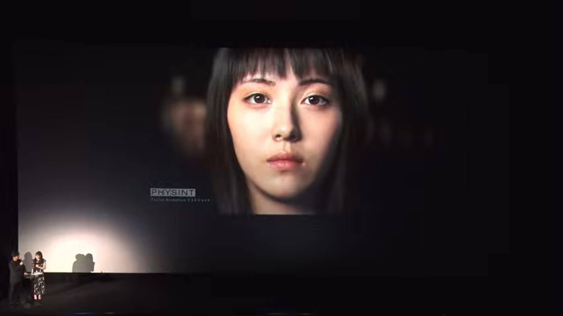 A screengrab of a livestream showing a big image of an actress face on a stage, as presented by Kojima Productions in their update about Physint.