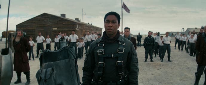 آرون مورتن در نقش ماکسیموس در Fallout.  آنها در خیابانی می ایستند که توسط مردم در زیر آسمان ابری احاطه شده است.