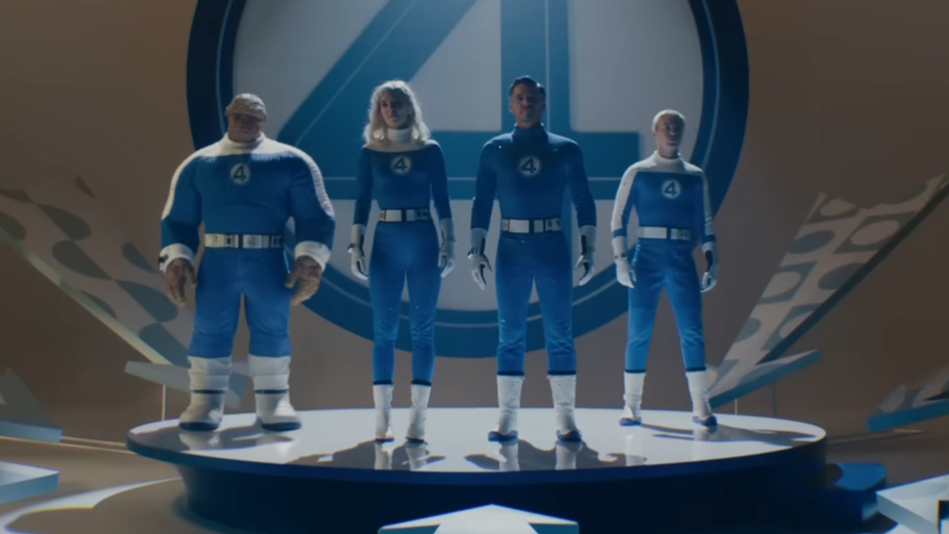 The titular Fantastic Four in First Steps all lined up on a stage wearing '60s era blue superhero costumes. - 6