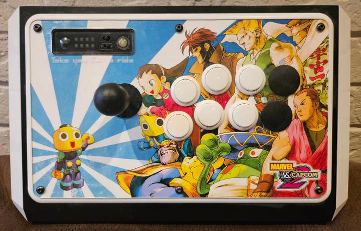 A MadCatz FightStick customized with Marvel vs. Capcom 2 characters including Tron Bonne, Gambit, Guile, Jin, Dan, Amingo, Thanos, and Servbot