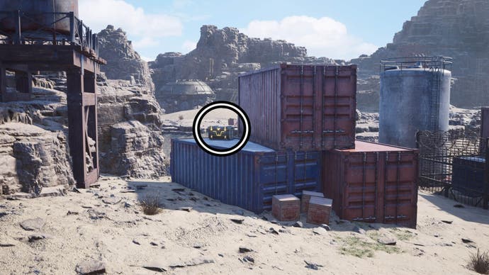A circle highlights a reward chest on a blue shipping container that's beside two red shipping containers.