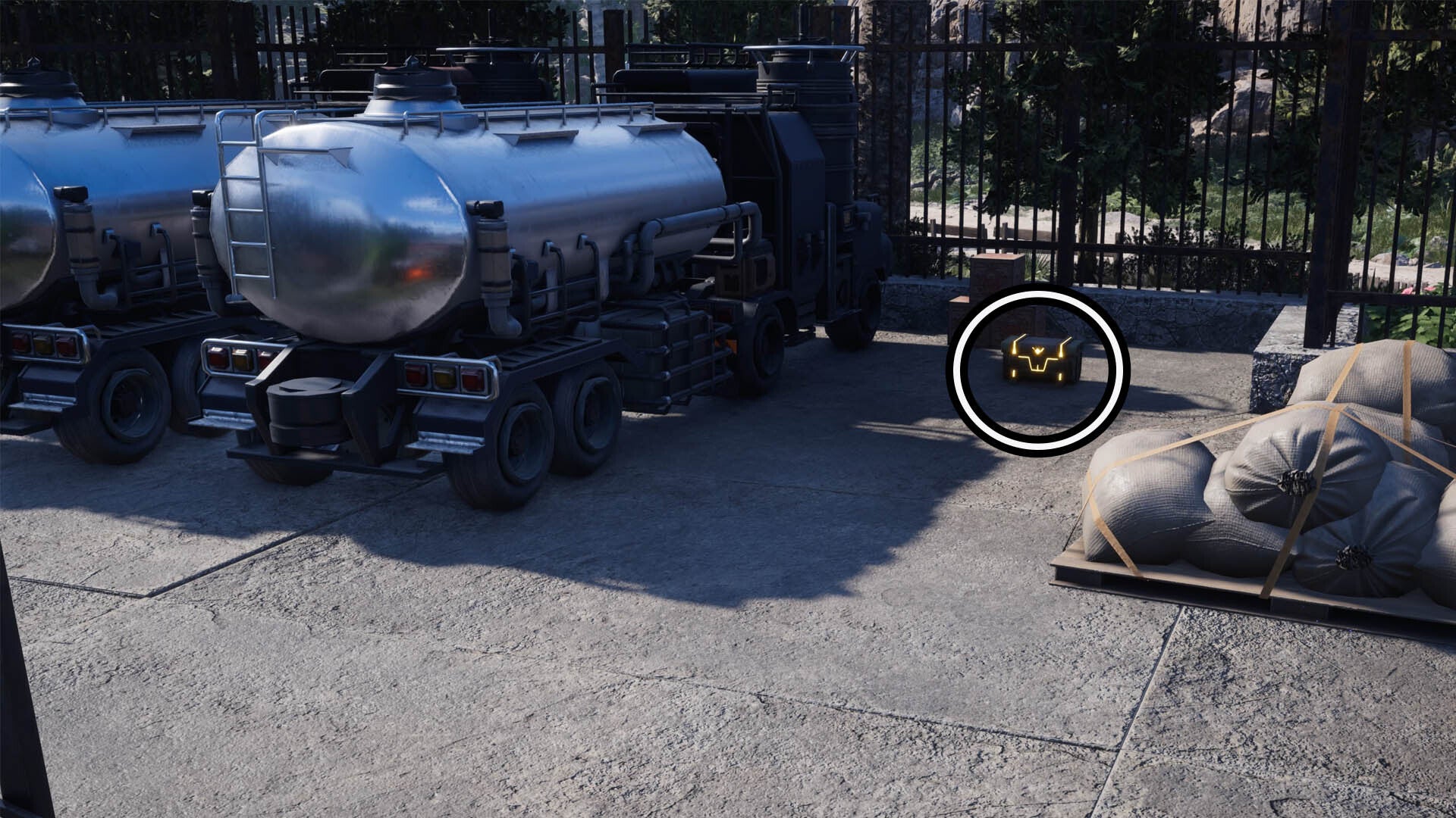 A circle highlights a reward chest that&rsquo;s on the ground beside two fuel tanker trucks.