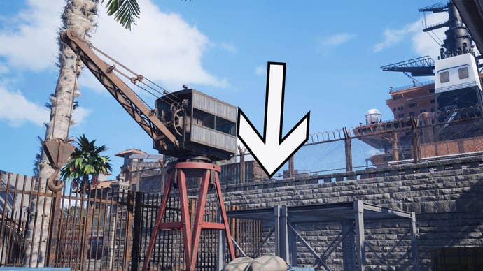 A large arrow is pointing down to the roof of a grey shelter behind a small crane against a stone wall.