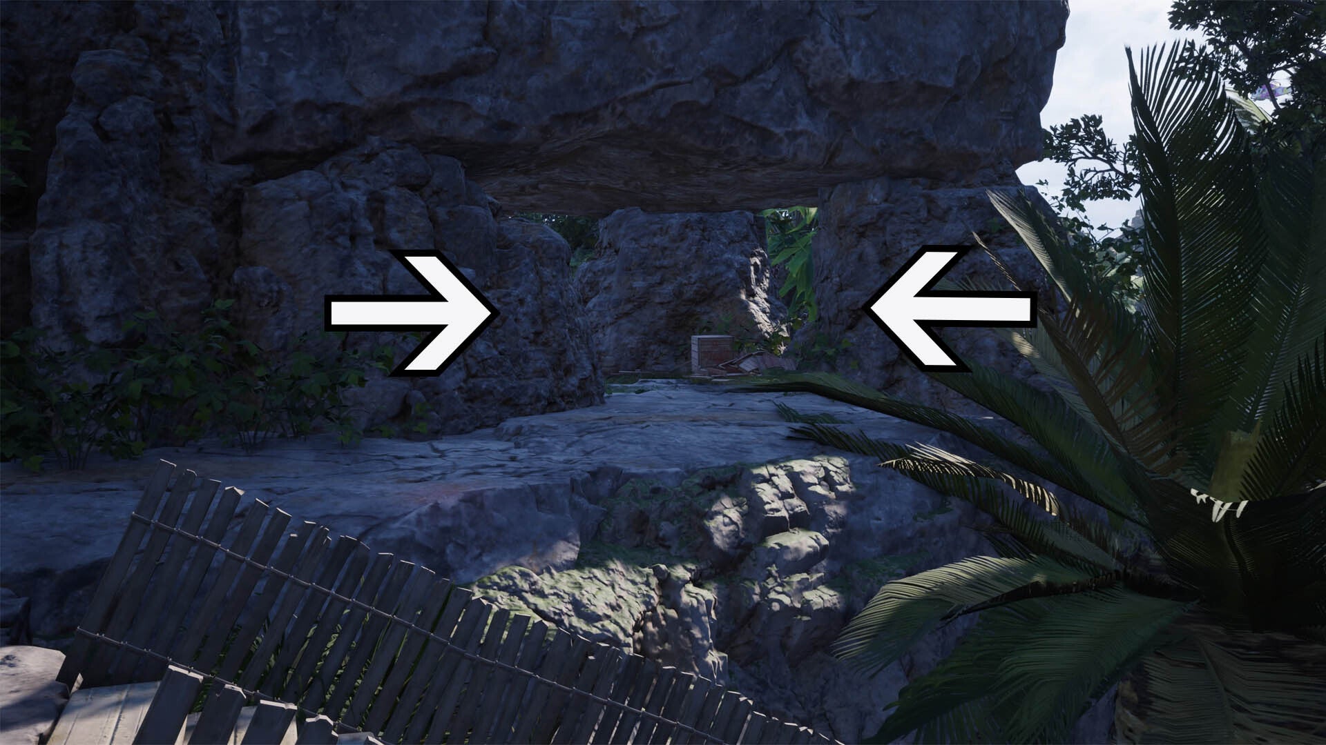 Two arrows point to an opening created by a few large rocks stacked around each other to make a doorway.