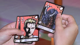 A close up of player hands holding some physical Triple Triad cards at Final Fantasy Fan Fest