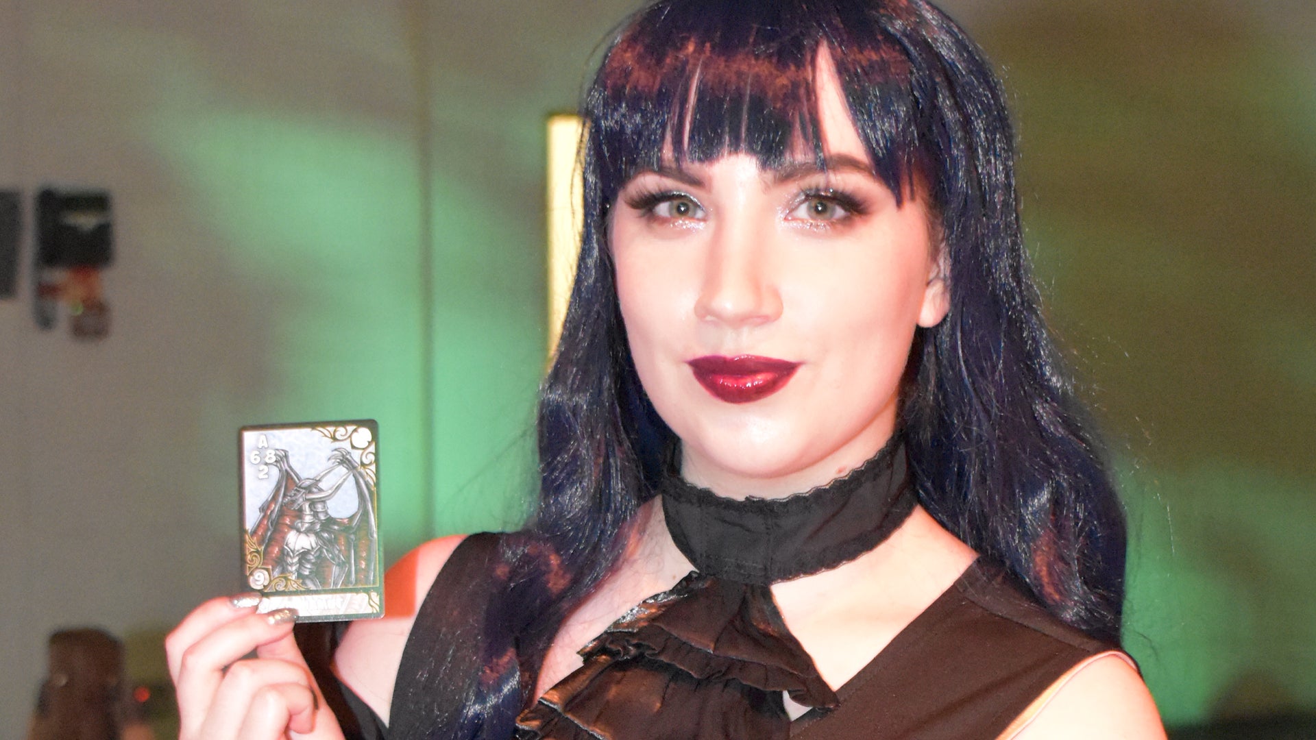 Ellie holds up a card won in a game of Triple Triad at Final Fantasy Fan Fest