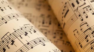 Rolls of cream-coloured musical parchment paper with music printed on them. Someone's got some practising to do.