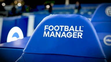 FM26 teaser video screenshot showing a football stadium bench seat with the Football Manager branding on the blue headrest