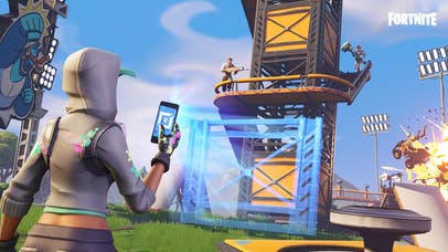 A Fortnite screenshot showing a player holding up a phone and the app on the phone is projecting a hologram of a new wall to build onto a fort