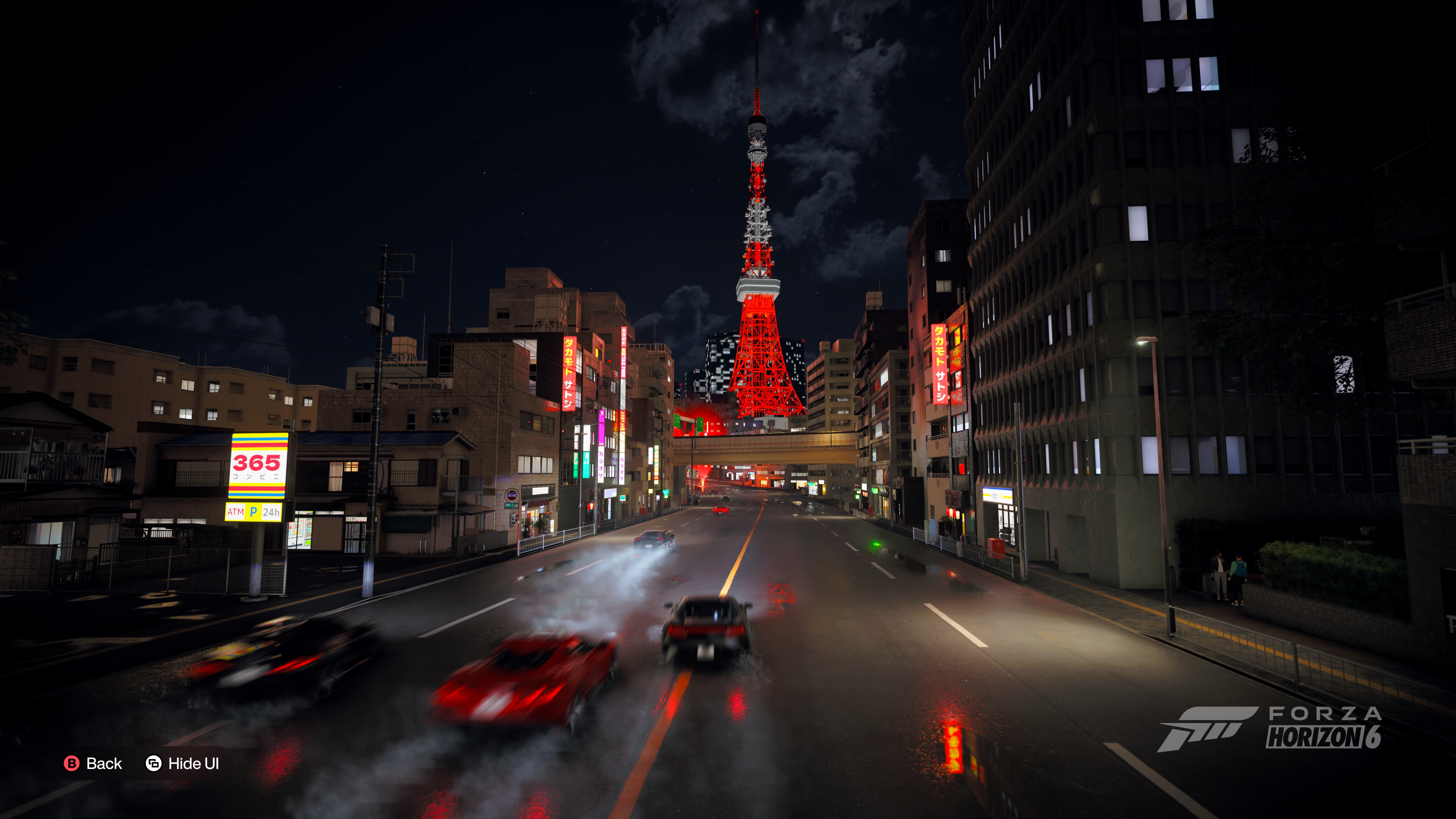 Tokyo tower at night in Forza Horizon 6 with three supercars blurred on the road before it