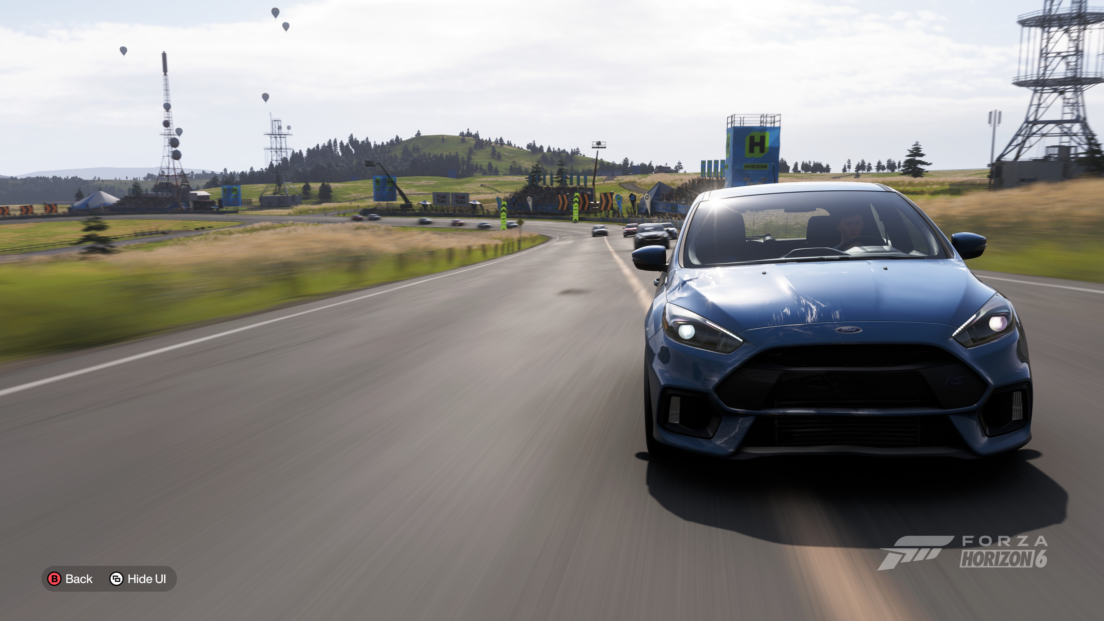 Slightly damaged car in Forza Horizon 6 with a road, panorama and hot air balloons in the distance behind
