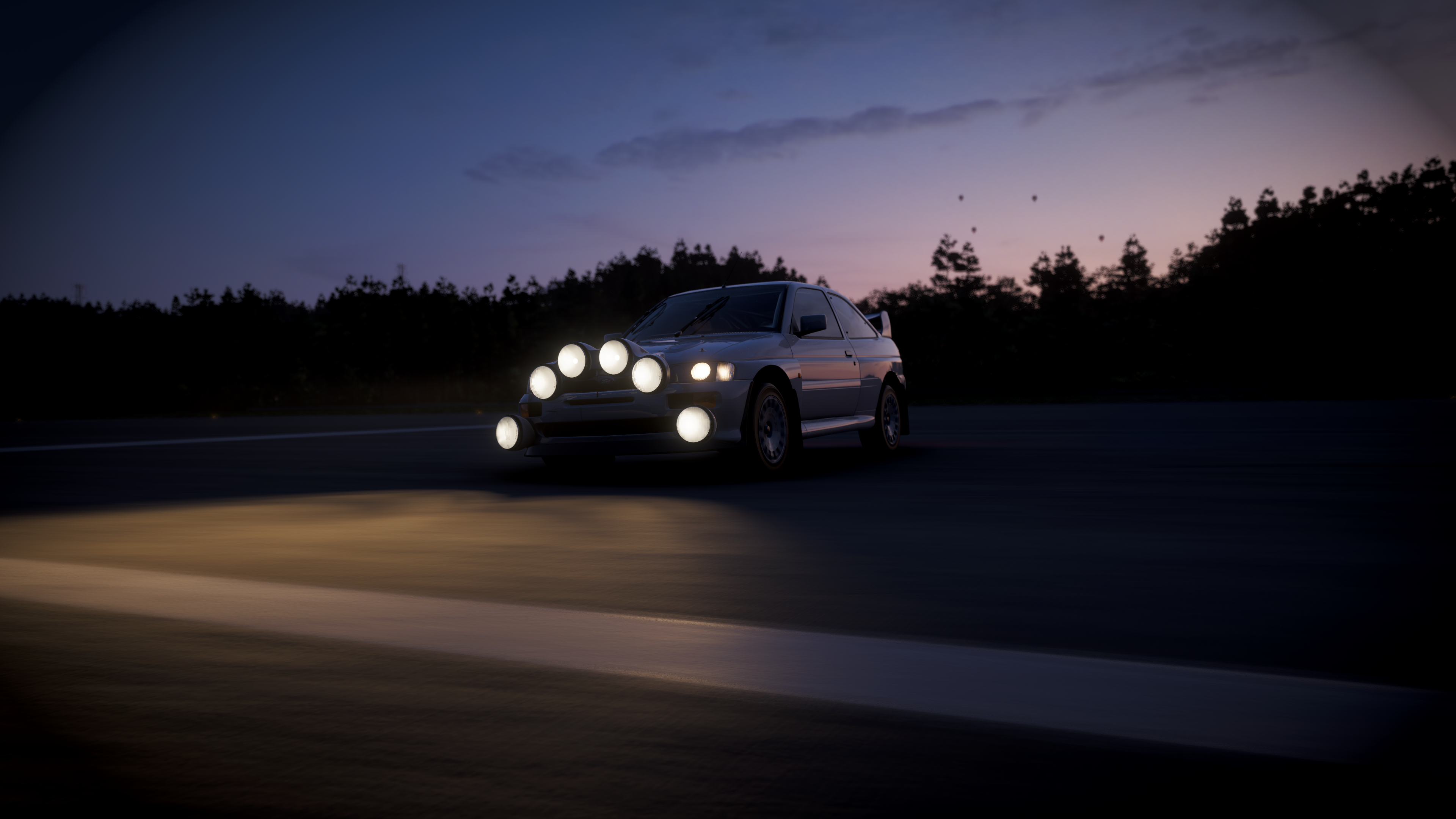 A 1992 Ford Escort RS Cosworth at night, headlights on and slightly obscuring the detail in dusky light