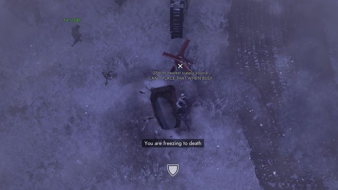 The player huddles in a foxhole while snow blankets the area and a message reads “you are freezing to death”.