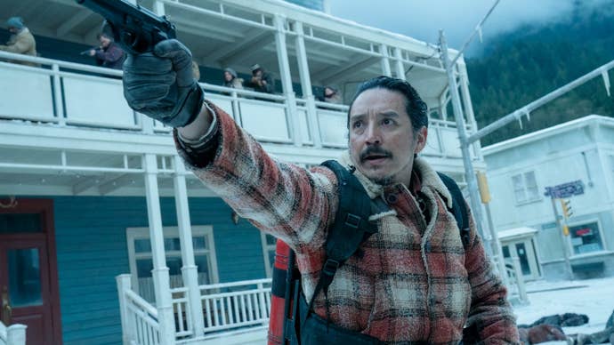 gabriel luna as Tommy in season two of The Last of Us. He is aiming a gun while defending Jackson