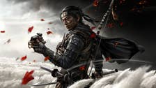 Ghost of Tsushima showing the main character, Jin, stood in a field of white feathery flowers, sword in one hand, mask in the other.
