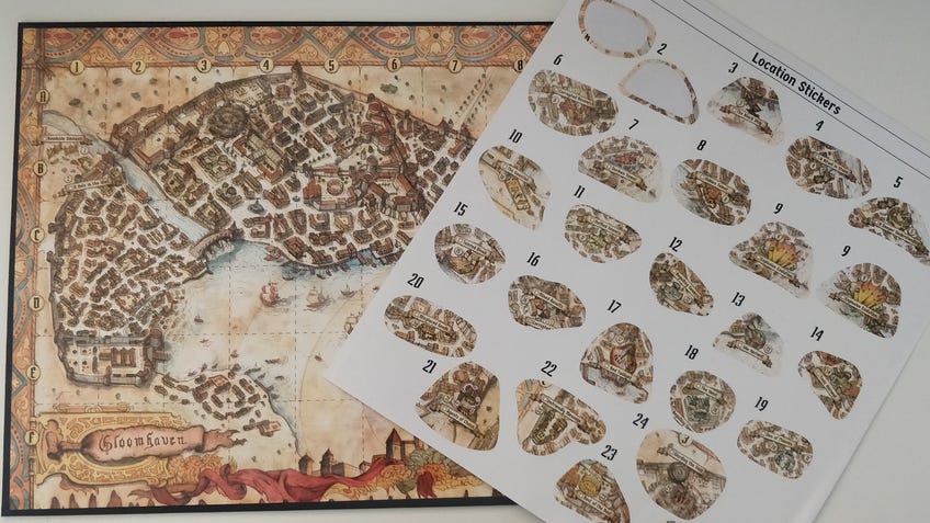 An image of the map board and sticker sheet for Gloomhaven: Jaws of the Lion.