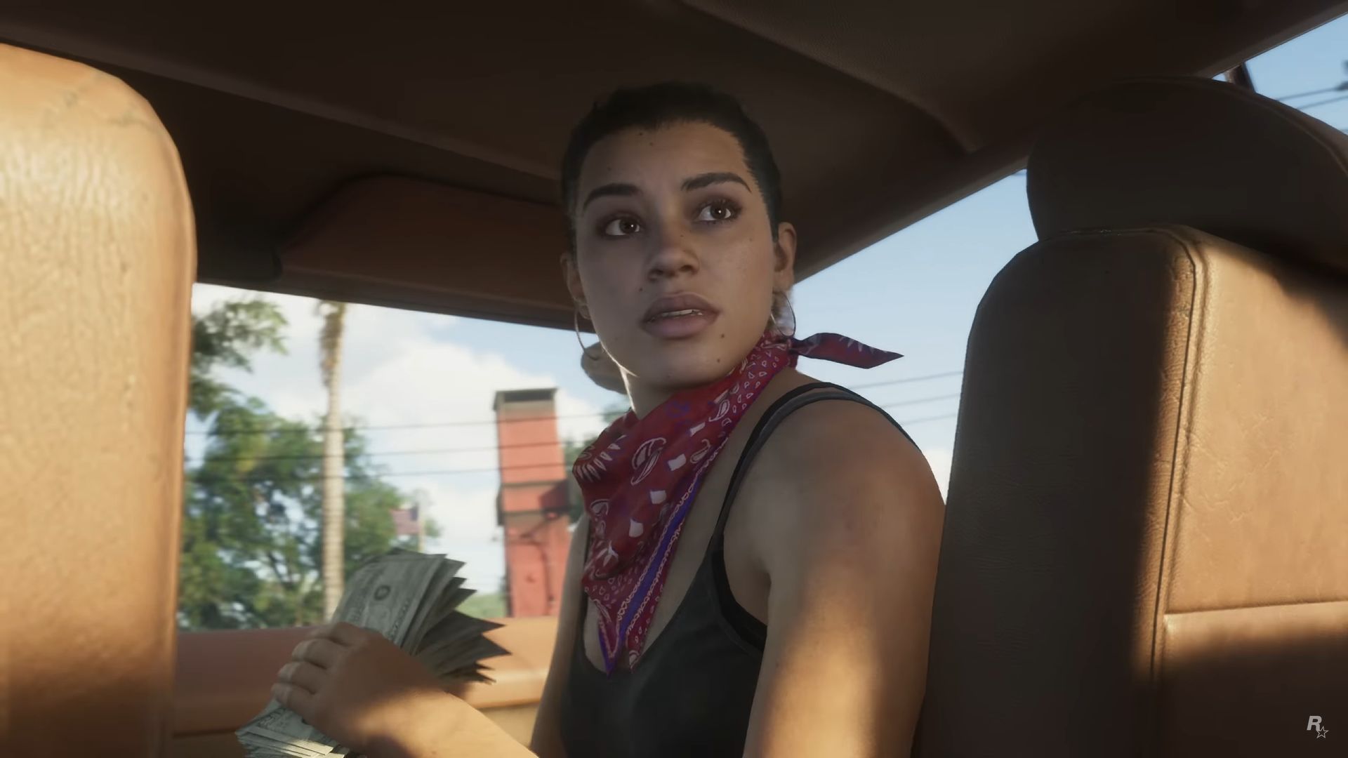 One of the protagonists of GTA 6 looks behind her seat in a car wearing a red bandana and holding a wad of cash. - 1