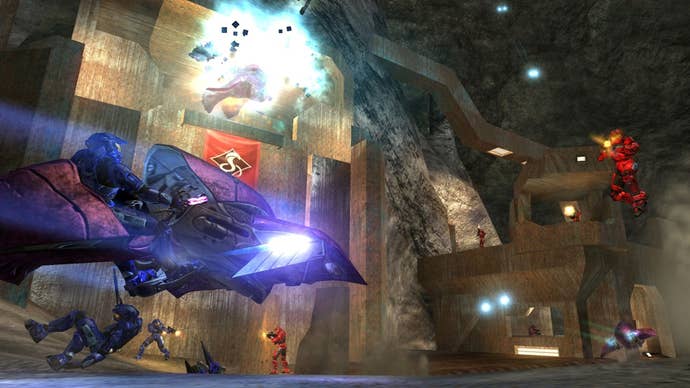 A multiplayer battle takes place in Halo 2, with a player racing at another in a Ghost while explosions happen in the background.