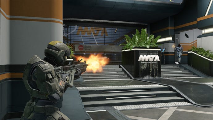 Two Spartans in Halo Infinite face off across the lobby of a transport station. The one in the foreground wields the VK78 Assault Rifle.