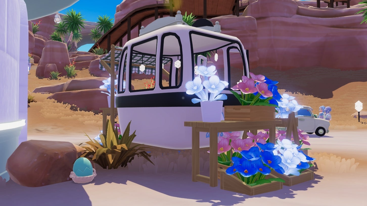 A white caravan with flowers displayed around its sides is parked near an igloo wall in an otherwise sunny desert area in Heartopia. A cyan egg is tucked behind a rock at the back of the van. - 7
